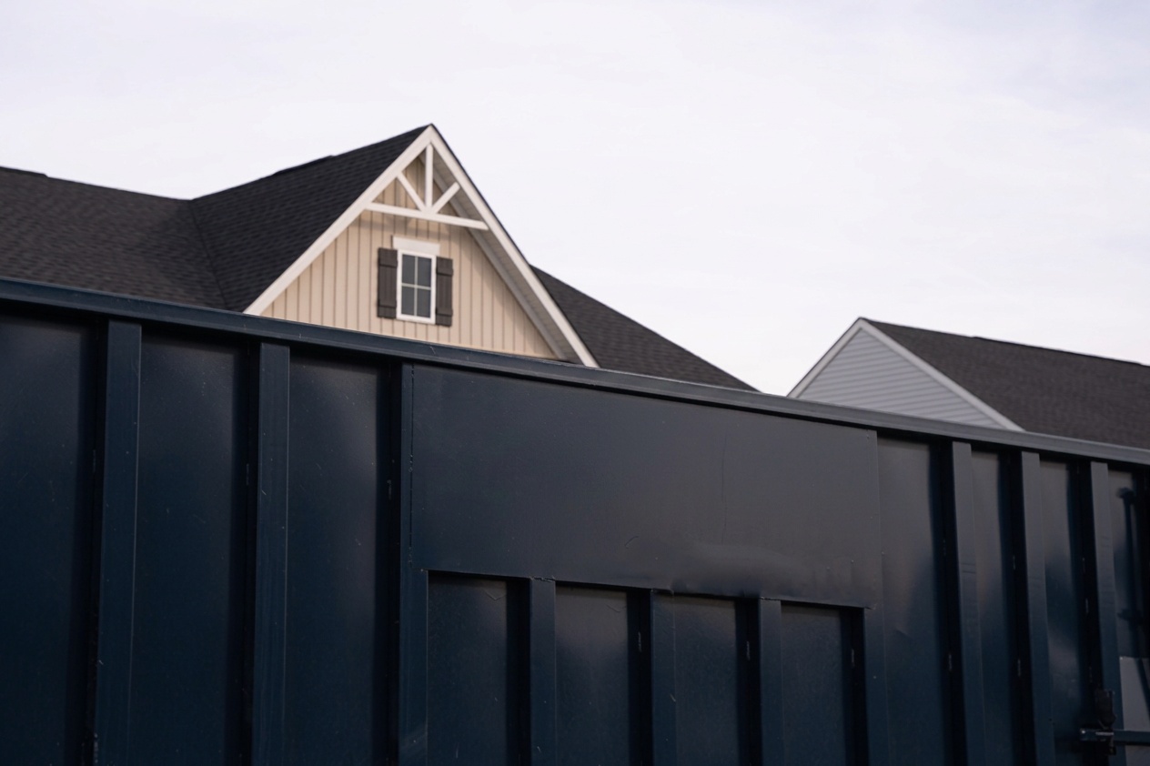 Close up image of blue dumpster in front of house with DumpstersRental365 logo.